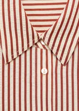 Camisa de corte recto y diseño a rayas verticales en tonos terracota y blanco, con cuello camisero, cierre frontal de botones y mangas largas con puños abotonados.