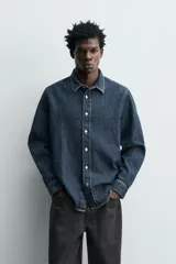 Camisa de corte relajado confeccionada en denim de algodón, con cuello solapa, manga larga con puños abotonados y cierre frontal de botones.
