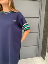 Vestido corto azul marino de hilo, con cuello redondo y mangas cortas con rayas verdes y blancas.