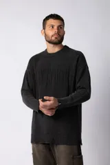 Sweater de punto grueso color negro con efecto gastado, cuello redondo, mangas largas y detalles de roturas en puños y ruedo. Presenta un diseño con letras bordadas al tono en el frente.