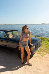 Top corto de diseño asimétrico con escote cruzado y mangas cortas, confeccionado en tela con estampado geométrico multicolor en tonos azul, verde y ocre.