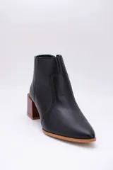 Botas cortas de cuero color beige, con punta fina y cierre lateral. Tienen un taco cuadrado de madera.