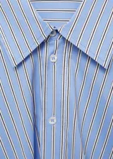 Vestido camisero corto de diseño cruzado con cierre frontal de botones. Presenta estampado de rayas verticales en tonos azul, blanco y negro, cuello camisero clásico y mangas largas con puños abotonados.