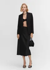 Blazer entallado de color negro con solapas de muesca, hombros estructurados y cierre frontal de un botón. Presenta bolsillos de ribete delanteros, abertura posterior y forro interior.