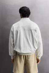 Sudadera de corte relajado con cierre frontal de cremallera, confeccionada en tejido ligero de mezcla de algodón. Presenta cuello subido, manga larga, bolsillos laterales ocultos en costura y acabados en rib.