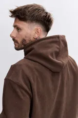 Buzo con capucha tipo canguro confeccionado en tela de corduroy color marrón. Presenta cordones blancos en contraste, bolsillo frontal tipo canguro y logo bordado sutil en el pecho.
