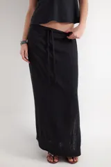 Falda larga de corte recto y tiro bajo en color negro, confeccionada en tejido plano dobby con textura rústica de mezcla de lino y viscosa. Cuenta con un cordón ajustable en la cintura.