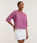Remera básica de algodón, color malva o fucsia apagado, con cuello redondo y manga corta que llega hasta el codo. Presenta un corte cropped y holgado.