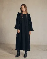 Vestido midi negro 100% algodón, de silueta amplia y relajada, con mangas largas abullonadas y detalles de volados en hombros y puños.