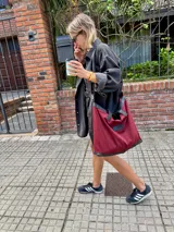 Bolso tote grande color bordó, con detalles en cuero negro en la base y las asas. Confeccionado en gabardina y forrado en tela Panamá.