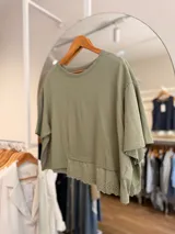 Remera oversize de color verde militar, con mangas cortas amplias y terminación inferior de puntilla bordada.