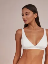 Soutien tipo halter de algodón color blanco, con diseño triangular y detalle de puntilla en los bordes.