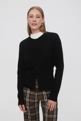 Saco negro de punto, con cuello redondo a la base, manga larga y cierre frontal con botones.