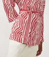 Cárdigan largo de punto con estampado geométrico en tonos rojo y blanco, manga larga, lazo en la cintura y abertura frontal sin botones.