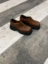 Zapato marrón de cuero con elástico en los laterales y suela de goma negra.