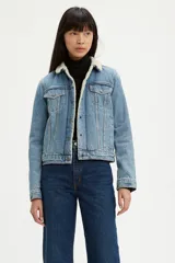 Campera de jean Levi's modelo Trucker, con interior y cuello forrados en corderito sintético color crema. Presenta cierre frontal con botones metálicos, bolsillos en el pecho con solapa y costuras reforzadas.