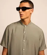 Camisa de manga corta con cuello tipo padre y cierre frontal de botones. Confeccionada en tejido texturizado de mezcla de viscosa y poliamida, con corte slim y acabado fluido.
