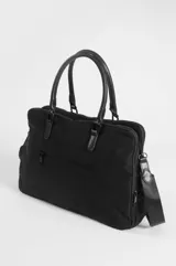 Briefcase negro de nylon con tres compartimentos, dos con cierre, bolsillo delantero con solapa y cierre de broche a presión. Cuenta con doble asa de mano, correa regulable y un llavero decorativo con cuentas coloridas colgando de uno de los herrajes.
