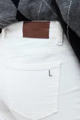 Pantalón de corte recto confeccionado en pana color crudo, con cierre frontal de botón y cremallera, y bolsillos laterales.