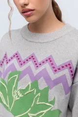 Sweater color camel de tejido de punto con cuello redondo y mangas largas. Presenta bordado de flor en el frente y la palabra 'Rebels' en la manga.