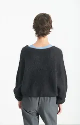 Polerón de punto negro con textura esponjosa, corte holgado y mangas largas. Presenta un diseño de cuello redondo y acabado suave al tacto.