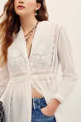 Camisa larga blanca de algodón estilo túnica, con detalles de encaje y bordados en el frente y mangas largas.