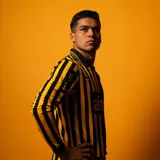 Camiseta de fútbol Puma de manga larga del Peñarol, edición aniversario 26, con diseño bicolor que combina mitades y rayas verticales en negro y amarillo, cuello tipo polo y detalles de sponsors en el frente.