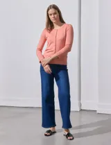 Cardigan blanco de tejido fino con abertura central y botones.