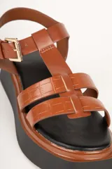 Sandalias negras de plataforma con tiras de símil cuero texturizado y hebilla metálica ajustable.