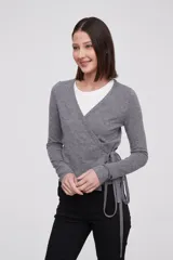Saco tipo cardigan cruzado de punto, color gris melange, con escote en V profundo, mangas largas y lazo lateral para ajustar a la cintura.