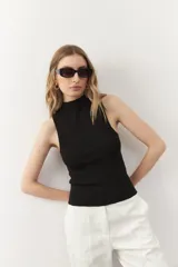 Musculosa negra de tejido de punto acanalado, con cuello alto y corte ajustado.