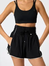 Short negro deportivo de tiro alto con pretina ancha elastizada, cordón de ajuste y detalles de ribetes blancos en los laterales y dobladillo. Incluye short interior integrado.