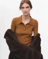 Jersey de punto color mostaza, con cuello polo y cierre frontal parcial de botones, de manga larga y diseño ajustado.