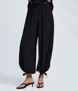 Pantalón estilo aladino color bordó, confeccionado en tejido crepé con textura. Presenta cintura elástica, corte holgado en las piernas y ruedo ajustado con lazo decorativo.