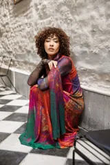 Vestido largo de tul con estampado abstracto en tonos violeta, fucsia, naranja y verde. Sin mangas, con cuello redondo y corte evasé. Incluye una bufanda de tul a juego.