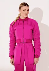 Campera bomber corta de cupro en color fucsia, con cuello alto, cierre frontal de cremallera metálica, y detalles fruncidos en las mangas y el canesú.
