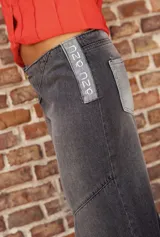 Jean de corte wide leg con diseño de paneles en diferentes tonos de gris y negro. Presenta cierre frontal con cremallera expuesta y costuras decorativas que crean un efecto de contraste.