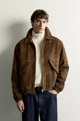 Cazadora de hombre regular fit confeccionada en tejido efecto ante, con acabado lavado, cuello solapa, manga larga, bolsillos de plastrón con solapa en la cadera, detalles elásticos en puños y cintura, y cierre frontal de cremallera.