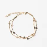 Pulsera de doble cadena tipo veneciana en color dorado, decorada con pequeñas esferas lisas y dijes en forma de estrella distribuidos a lo largo de ambas cadenas.