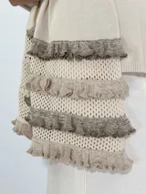Chal de punto color beige con textura calada y volados en los bordes.