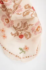 Bandana de algodón color crudo con diseño bordado en punto cruz que incluye motivos florales, corazones y conejos.