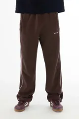 Pantalón de jogging marrón con corte recto, cintura elástica y cordón ajustable. Cuenta con bolsillos laterales y una línea vertical blanca a lo largo de la pierna.