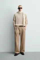 Sweater de punto con diseño de trenzas, color beige, cuello redondo y manga larga con terminaciones en rib.