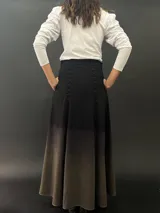 Falda larga de lana color negro con teñido degradado en tonos grises. Corte a la cintura con bolsillos laterales y cierre invisible.