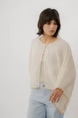 Blusa de lino color blanco, de diseño holgado, manga larga amplia acampanada con detalles de bordado en los puños y cuello redondo.
