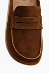 Sandalias mules tipo mocasín de gamuza color marrón, con diseño destalonado y suela de corcho y goma.