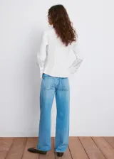 Camisa de popelín blanco entallada, con cuello camisero, mangas largas y cierre frontal de botones ocultos.