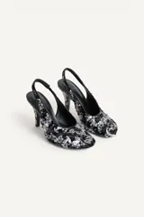 Zapato de tacón destalonado con abalorios y lentejuelas en tonos negros y plateados, escote redondo, punta redonda y tacón fino alto.