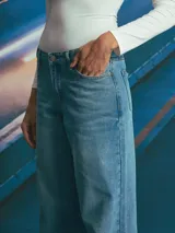 Jean de corte recto y tiro medio, confeccionado en denim de tono azul medio con costuras en contraste. Presenta diseño de cinco bolsillos y cierre frontal con botón metálico.