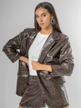 Blazer de mujer color marrón chocolate, confeccionado en ecocuero texturizado con acabado acharolado. Es forrado y presenta un corte estructurado con solapas y bolsillos frontales.